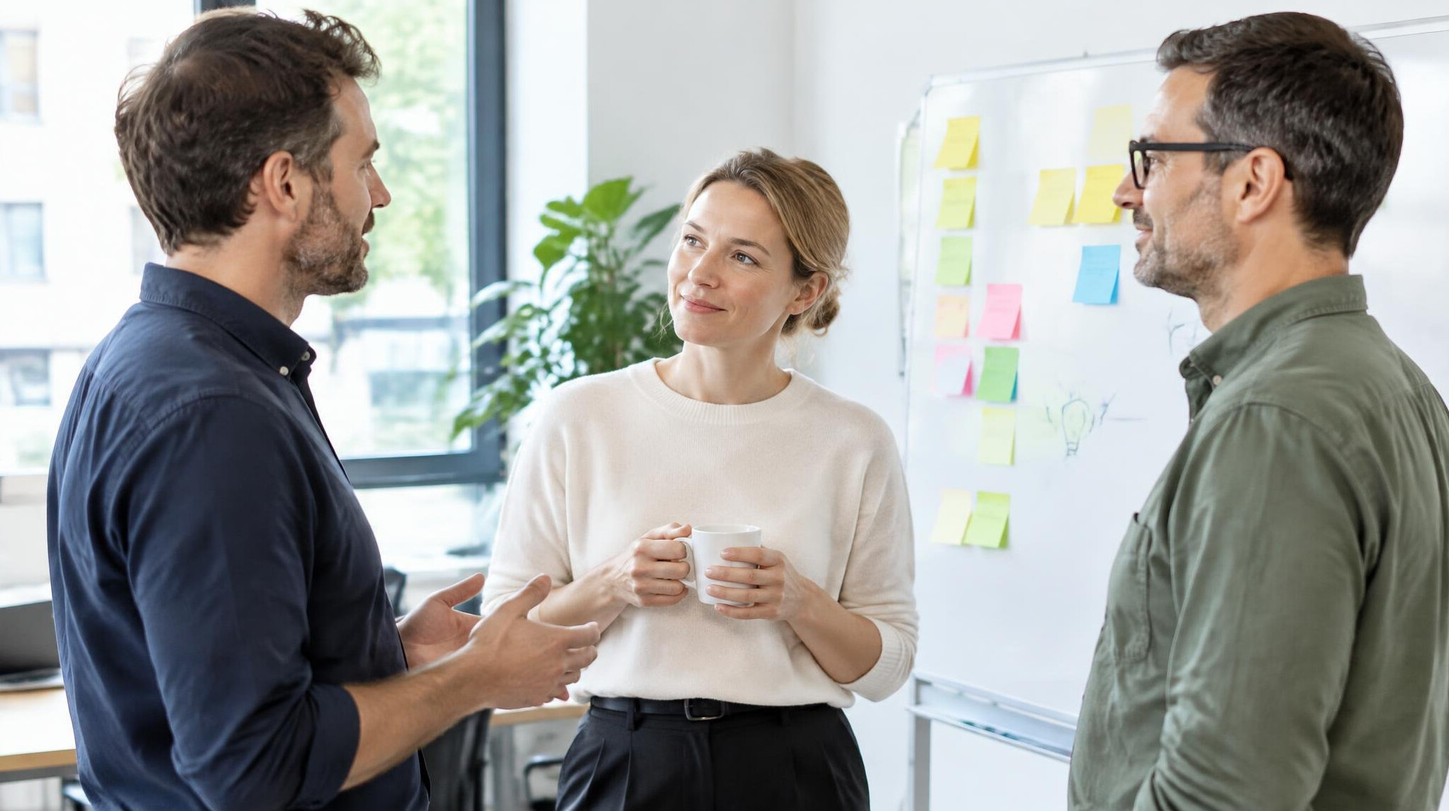Small group of colleagues having a conversation near a whiteboard